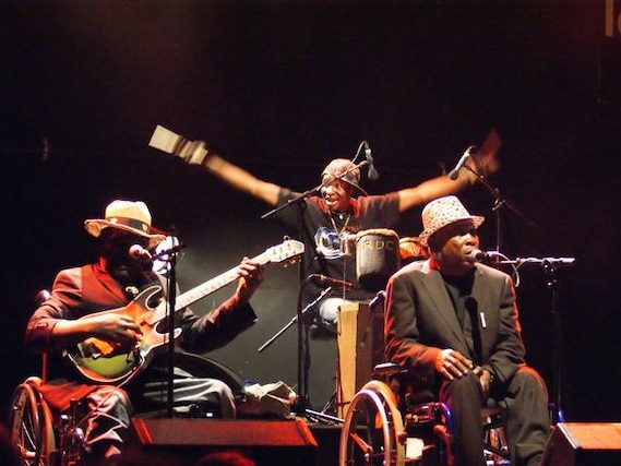 Bras levés, les membres de Staff Benda Bilili répondent aux vivats largement mérités du public yonnais conquis par une musique originale faite des sonorités uniques, exceptionnelles|Photo : © AEM
